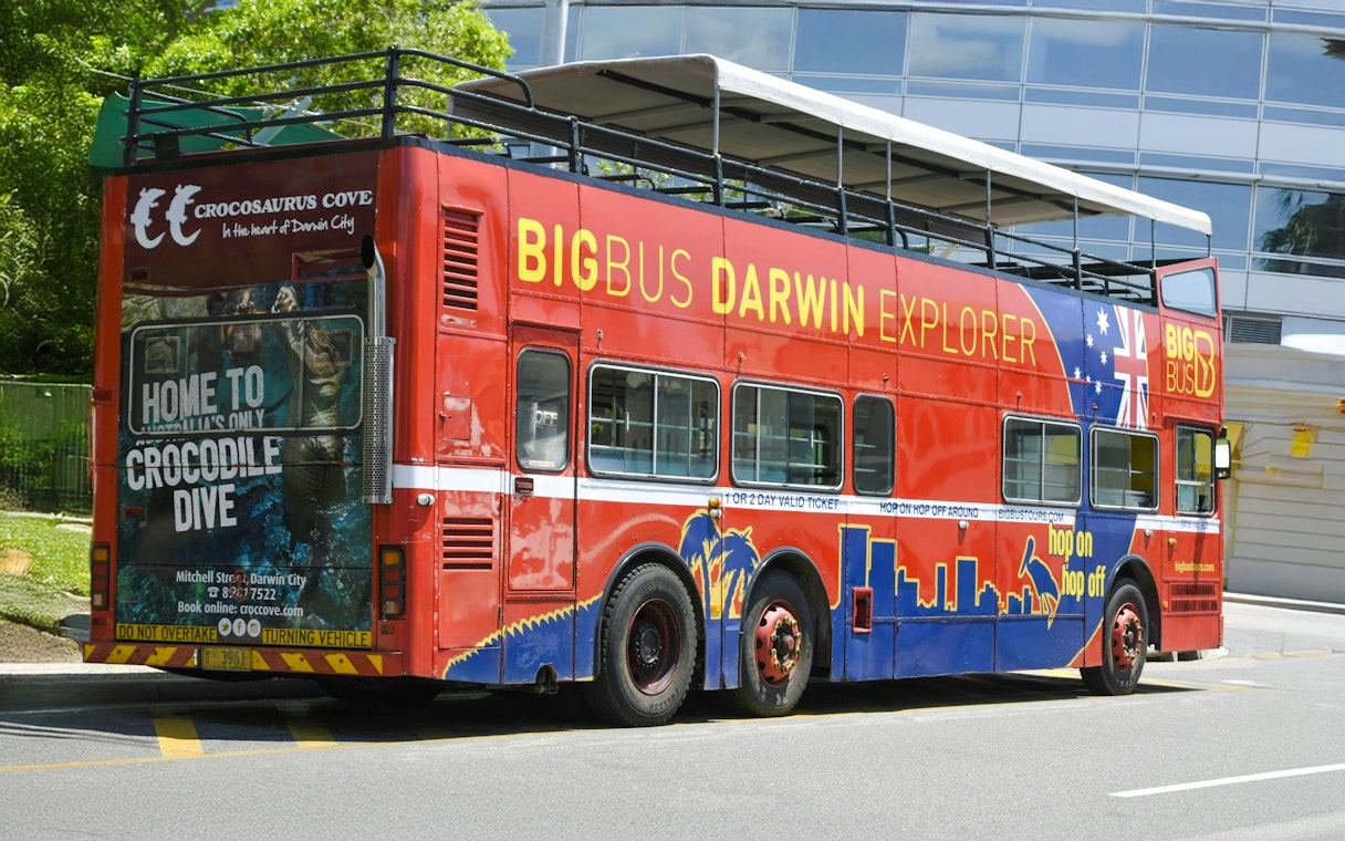 Big Bus Darwin Explorer parked near Crocosaurus Cove, promoting hop on hop off tours.