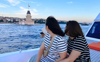 Visitors on a private luxury yacht viewing Maiden's Tower at sunset in Istanbul.