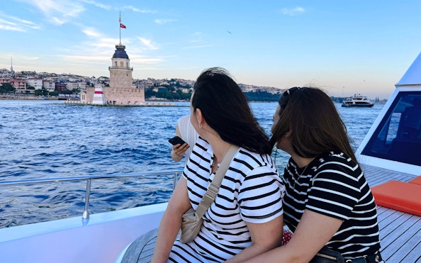 Visitors on a private luxury yacht viewing Maiden's Tower at sunset in Istanbul.