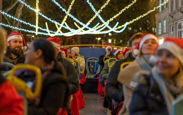 Passengers in Santa hats on a Tootbus enjoying London Christmas lights.