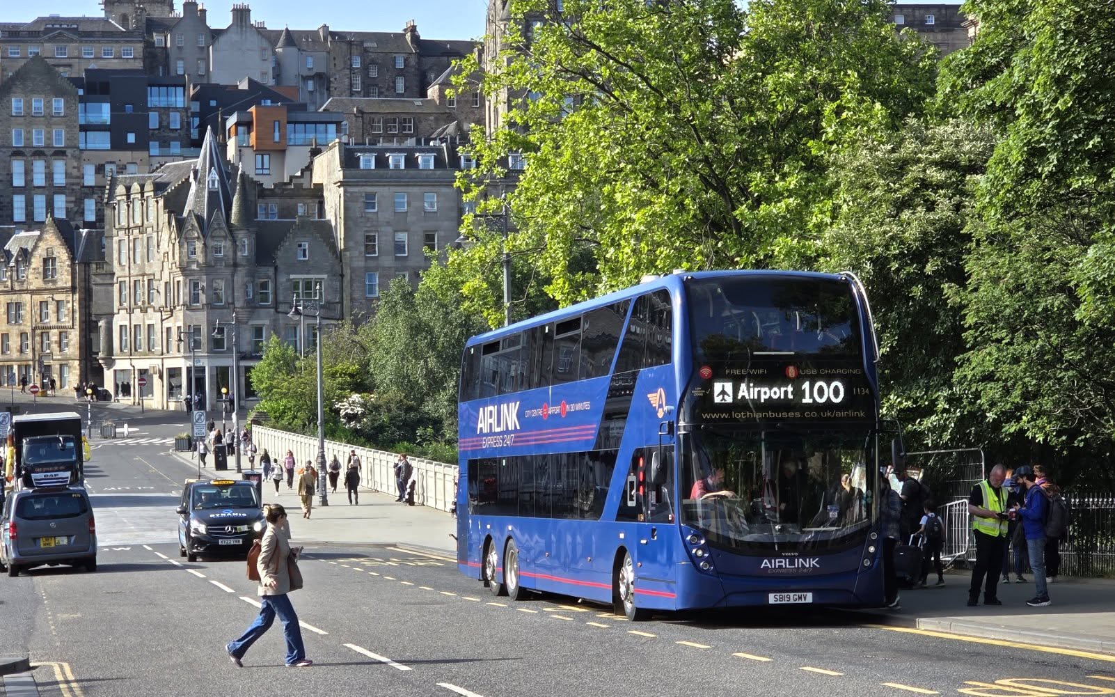 Edinburgh Airlink bus on city street with historic buildings in background.