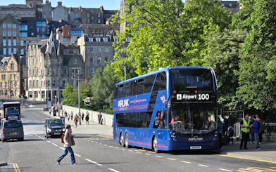 Edinburgh Airlink bus on city street with historic buildings in background.