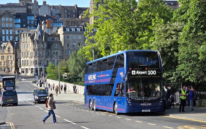 Edinburgh Airlink bus on city street with historic buildings in background.