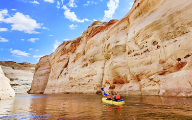 Kayakers paddling on Lake Powell near Antelope Canyon's sandstone cliffs.