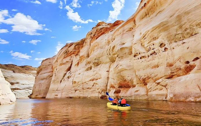 Kayakers paddling on Lake Powell near Antelope Canyon's sandstone cliffs.