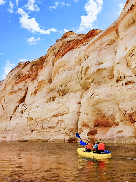 Kayakers paddling on Lake Powell near Antelope Canyon's sandstone cliffs.