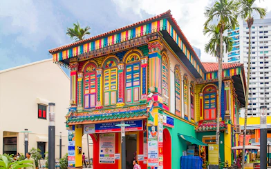 Colorful heritage building in Little India, Singapore, featuring vibrant architecture and palm trees.