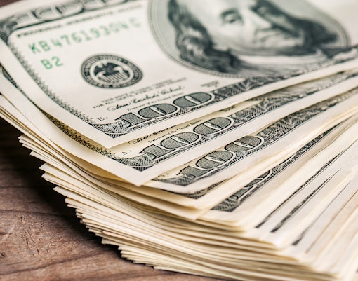 Stack of US dollar bills representing savings.