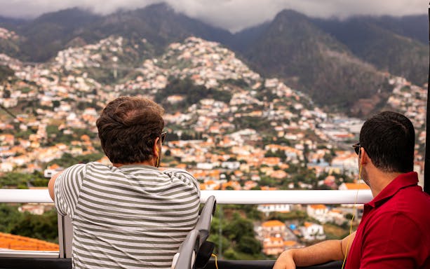 Tourists on a Funchal bus tour overlooking the cityscape and mountains.