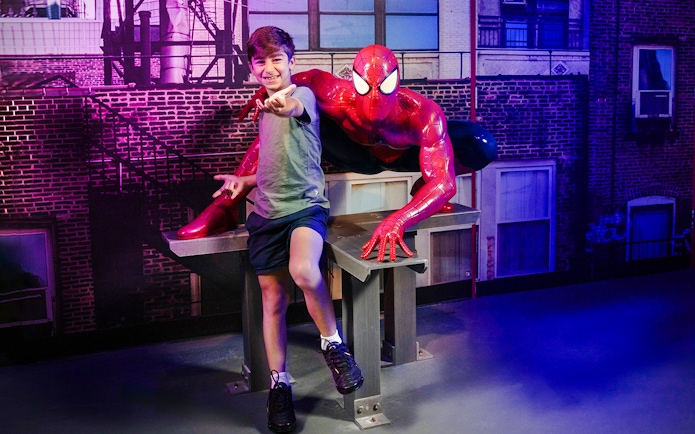 Child posing with Spider-Man figure at Madame Tussauds Sydney.
