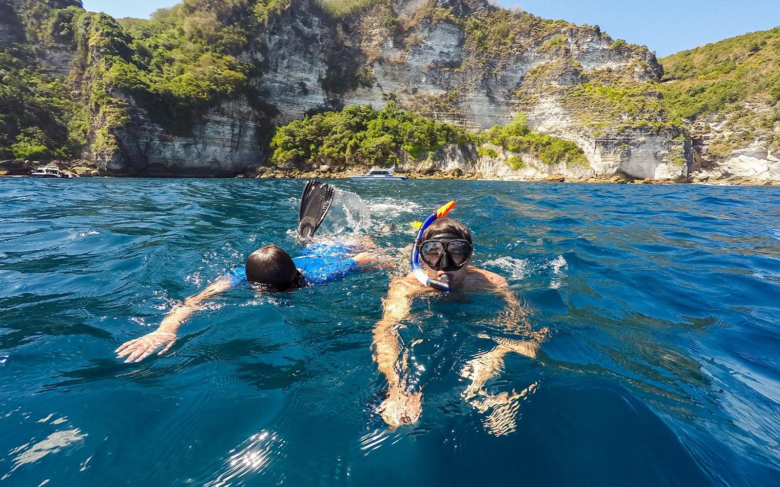 Snorkelers exploring the waters near cliffs on Nusa Penida Island.