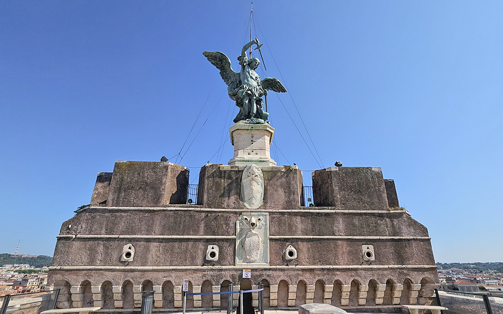 Archangel Michael statue atop Castel Sant'Angelo against a clear blue sky
