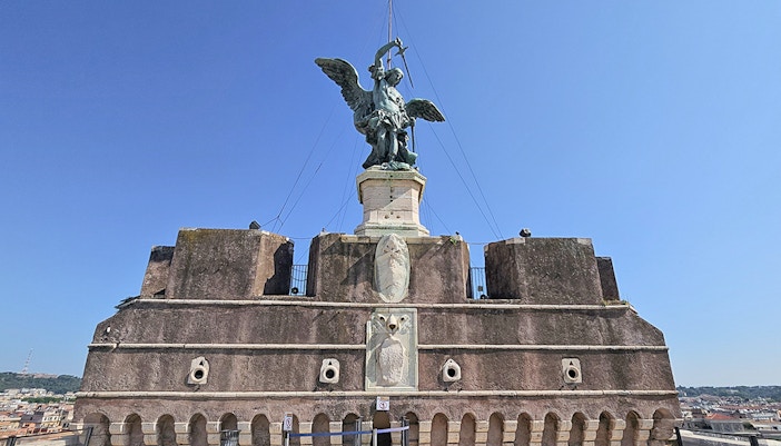 Archangel Michael statue atop Castel Sant'Angelo against a clear blue sky