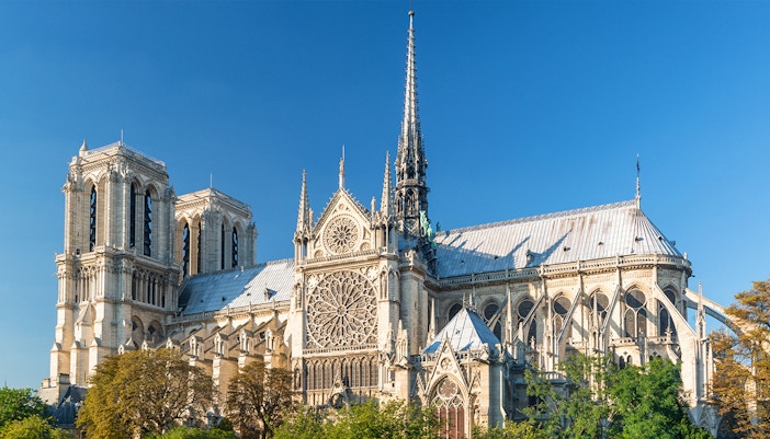 Notre Dame Cathedral facade in Paris with tourists exploring the historic site.