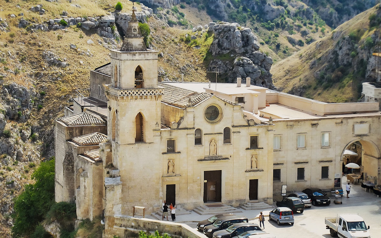 Historic church facade in Matera, Italy, surrounded by rocky landscape.