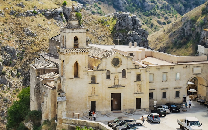 Historic church facade in Matera, Italy, surrounded by rocky landscape.