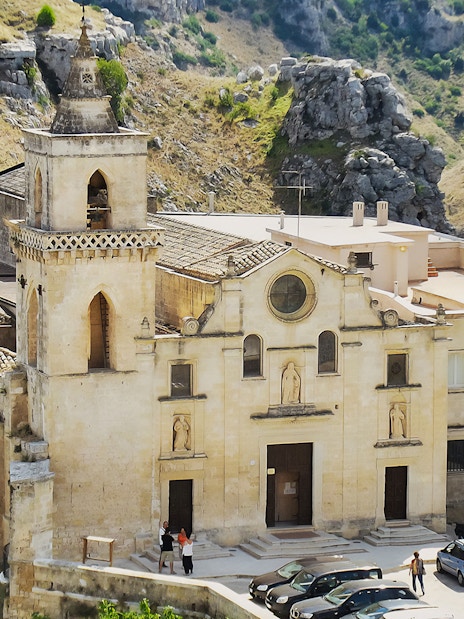 Historic church facade in Matera, Italy, surrounded by rocky landscape.