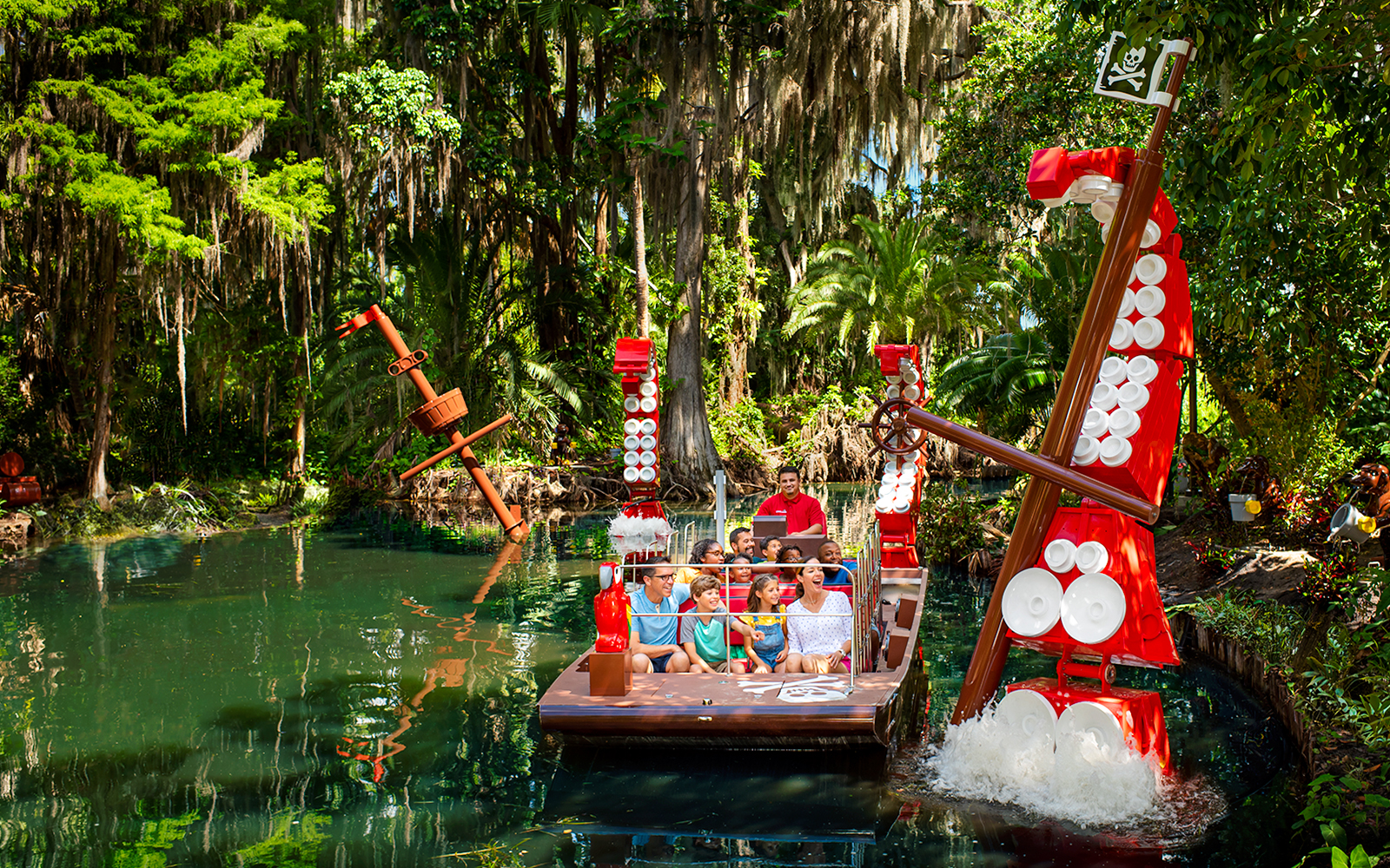 Visitors on a boat ride through a lush, pirate-themed river at Legoland Florida.