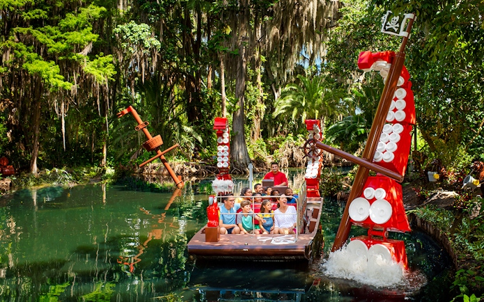 Visitors on a boat ride through a lush, pirate-themed river at Legoland Florida.