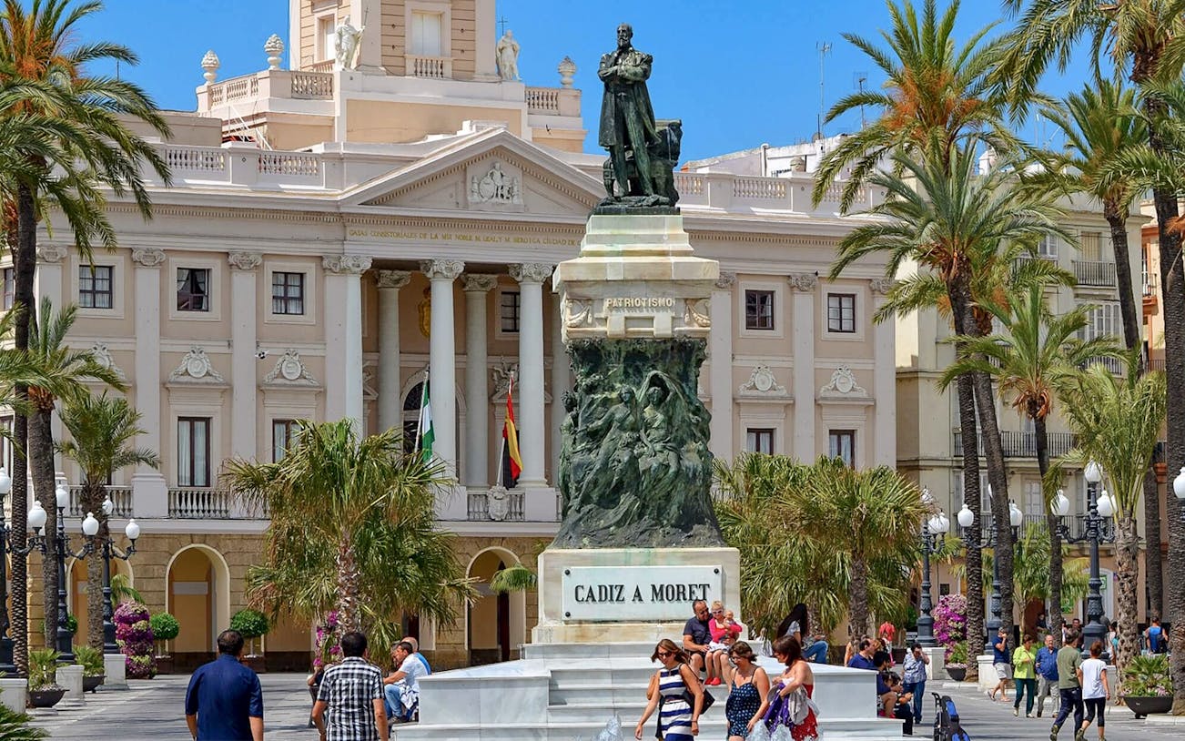 Statue of Moret in front of Cádiz City Hall, Spain, with people walking nearby.
