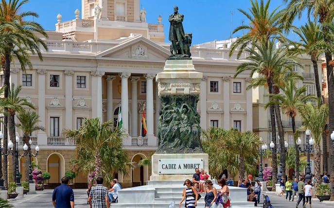 Statue of Moret in front of Cádiz City Hall, Spain, with people walking nearby.