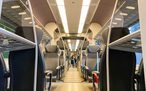Interior of Malpensa Express train with empty seats and overhead luggage racks.