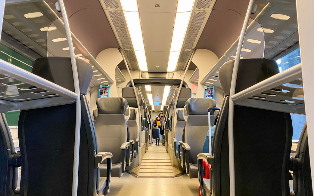 Interior of a train with empty seats, part of Milan airport to city center travel package.
