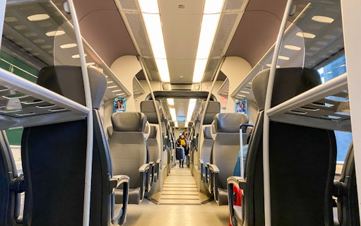 Interior of a train with empty seats, connecting Milan Malpensa Airport and Milan Cadorna Station.