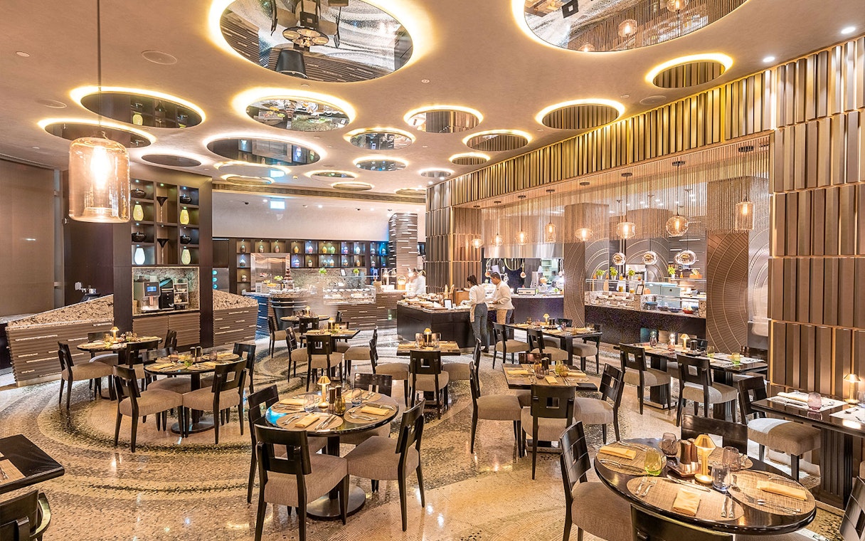 Buffet dining area at Mundo Jumeirah Emirates Towers with tables and food stations.