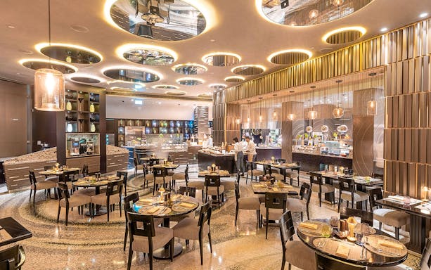 Buffet dining area at Mundo Jumeirah Emirates Towers with tables and food stations.