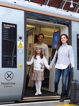 Family exiting Heathrow Express train at station platform.