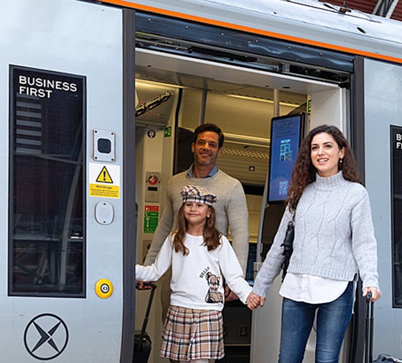 Family exiting Heathrow Express train at station platform.