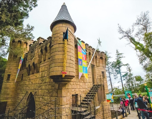 Castell dels Contes stone castle with colorful banners and visitors in line.
