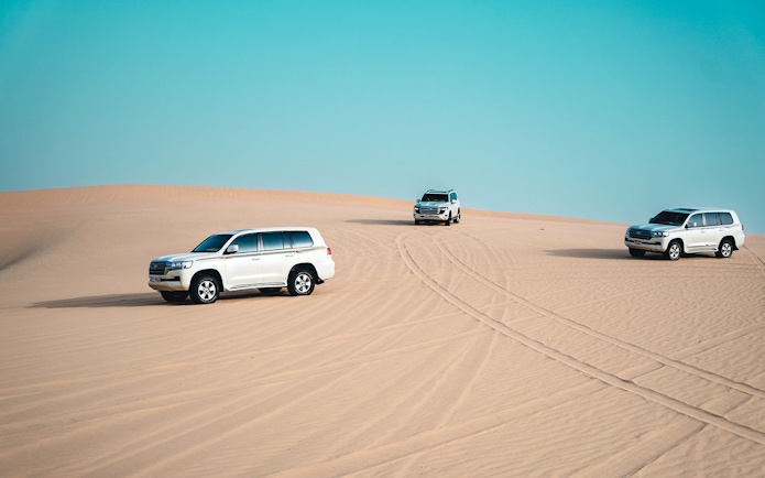 4x4 Jeeps driving on sand dunes in Abu Dhabi desert.