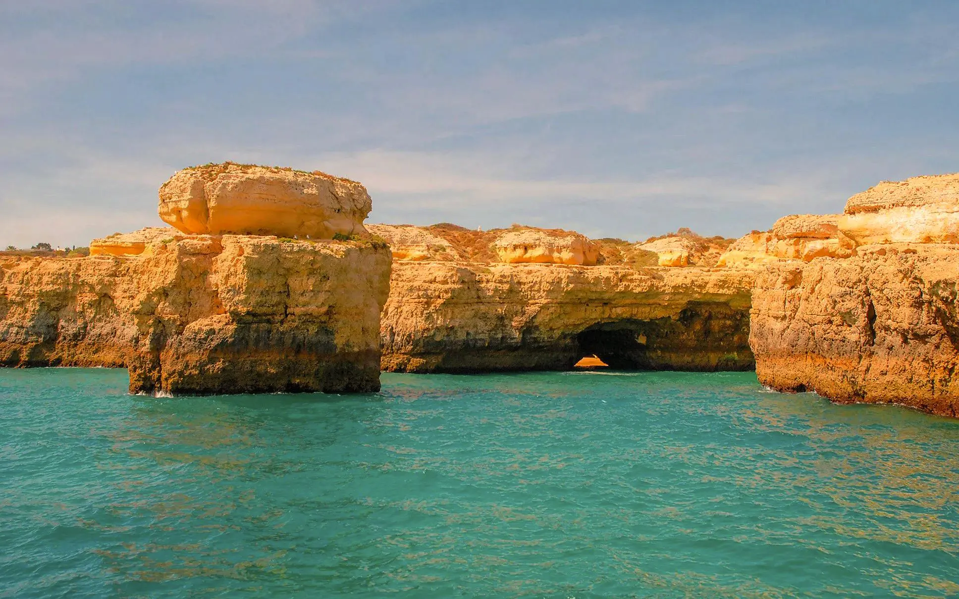 Rock formations and sea cave along the Algarve coast at sunset.