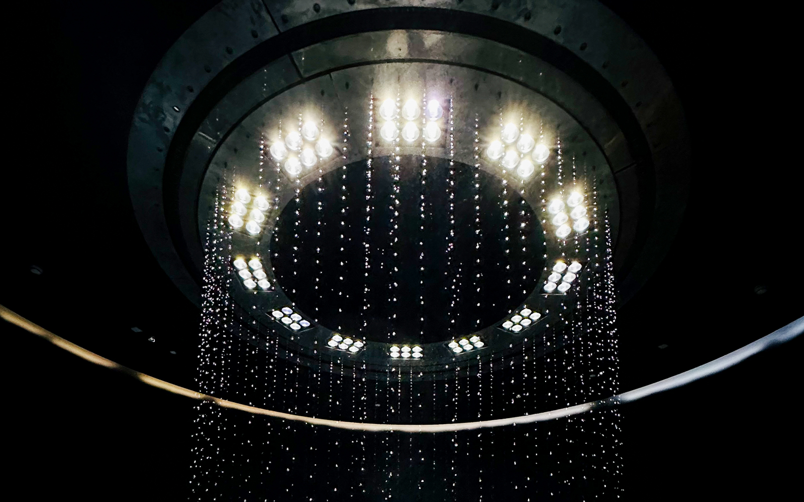 Visitors exploring The Fall at AYA Universe, Dubai, with cascading water features and vibrant lights.