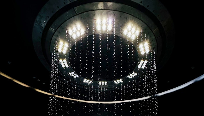 Visitors exploring The Fall at AYA Universe, Dubai, with cascading water features and vibrant lights.