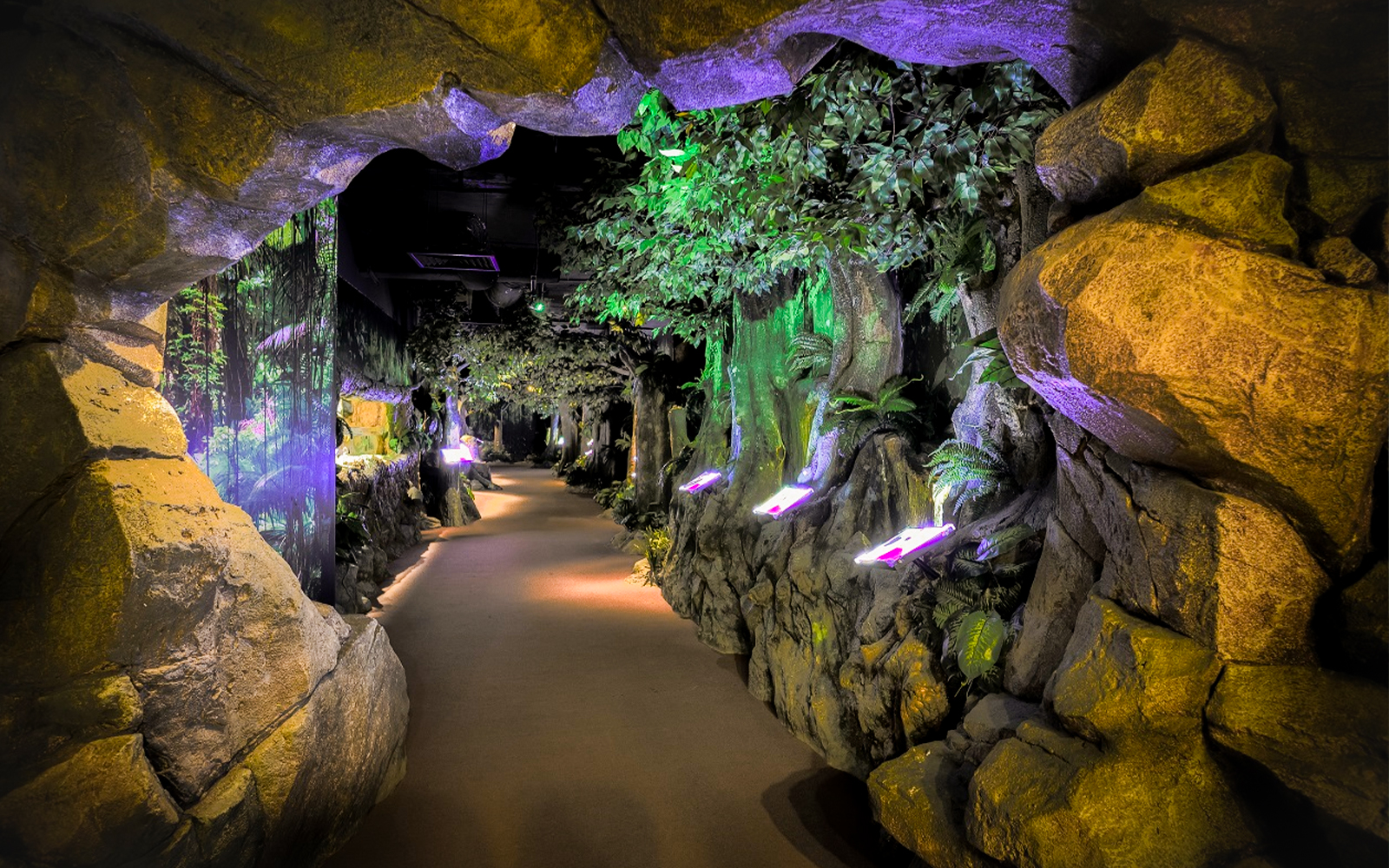 Pathway through illuminated cave and forest exhibit at The TOP Penang.