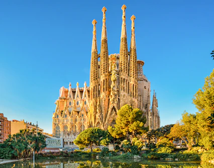 Sagrada Familia in Barcelona, Spain, illuminated during golden hour with surrounding trees and buildings.