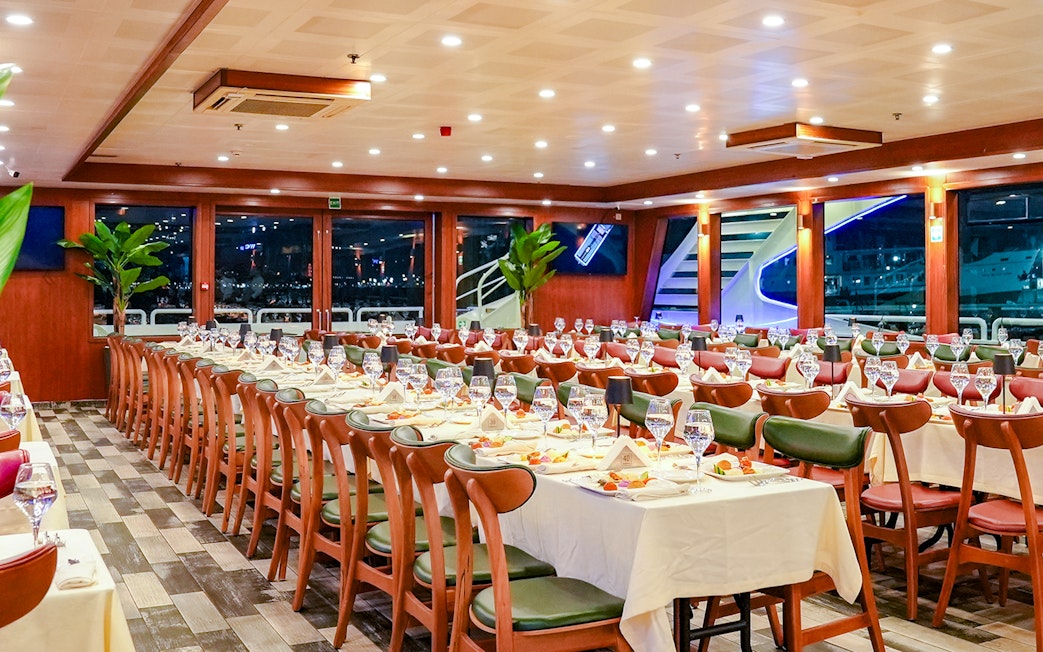 Dinner tables set for Bosphorus 4-Course Dinner Cruise, featuring elegant table settings and large windows.