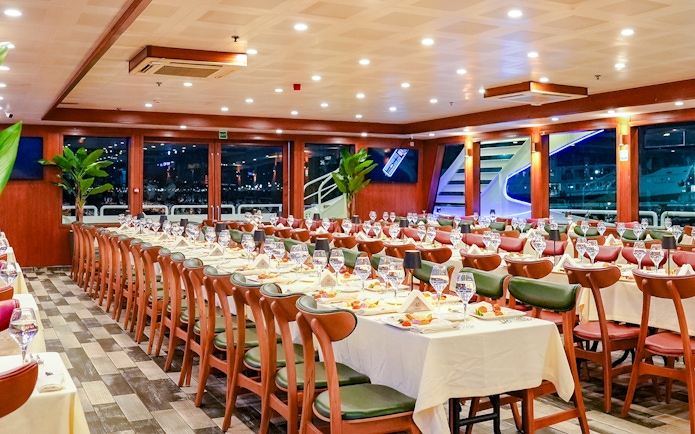 Dinner tables set for Bosphorus 4-Course Dinner Cruise, featuring elegant table settings and large windows.