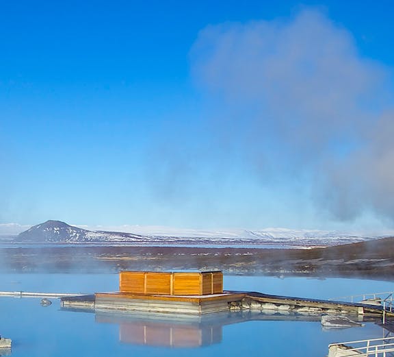 Myvatn Nature Baths with steaming geothermal waters and distant snow-capped mountains in Iceland.