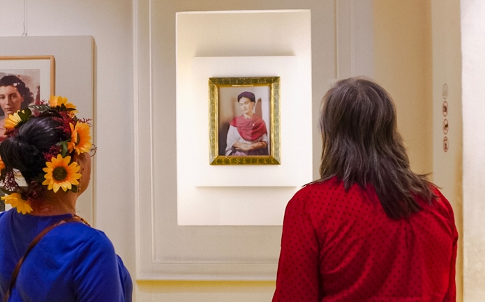 Visitors viewing a portrait of Frida Kahlo at the Frida Kahlo Museum.