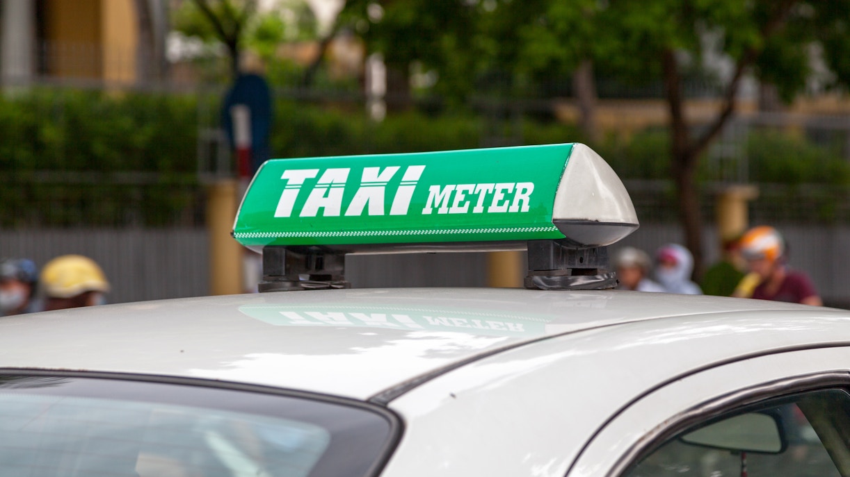 Vietnamese taxi with green "Taxi Meter" sign on roof.