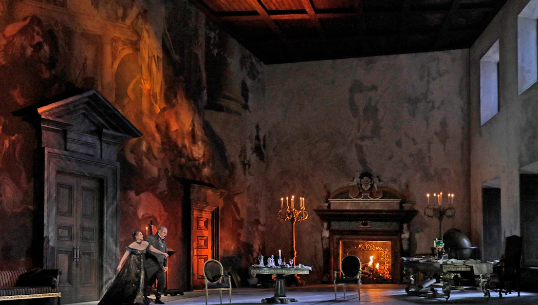 Opera scene from Tosca with performers on stage in an ornate room with a fireplace.