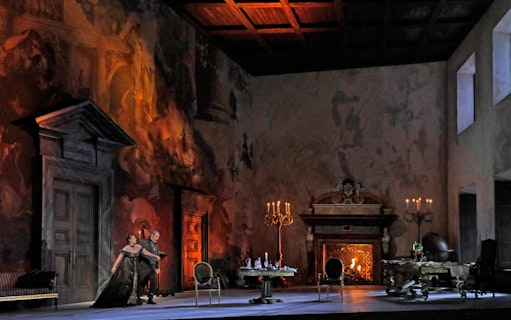 Opera scene from Tosca with performers on stage in an ornate room with a fireplace.
