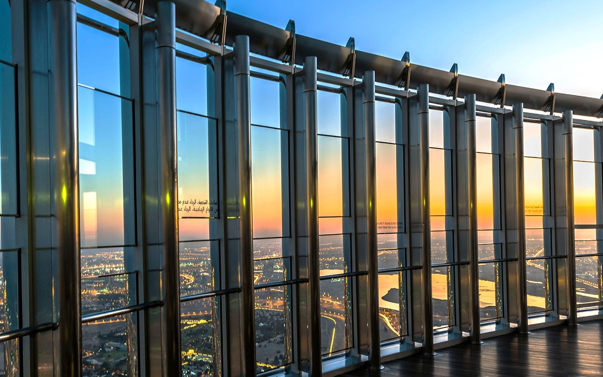 View from Burj Khalifa Level 124 at sunrise, overlooking Dubai cityscape.