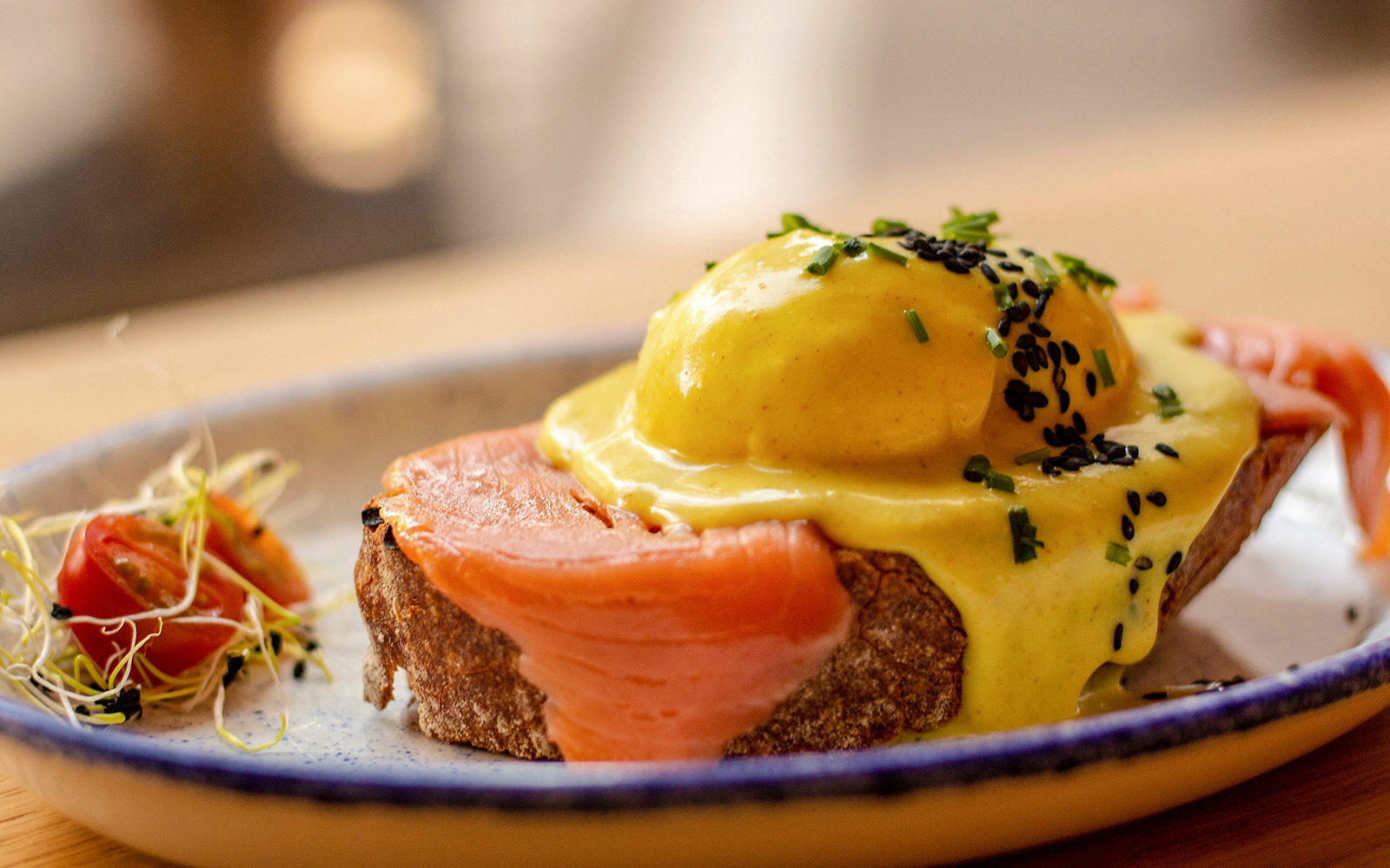 Salmon tostada with poached egg and hollandaise sauce on a plate.