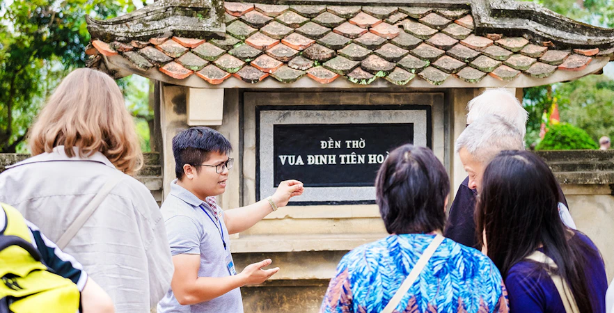 Tour guide explaining Đinh Tiên Hoàng Temple to visitors at Hoa Lư Ancient Capital, Ninh Bình, Vietnam.