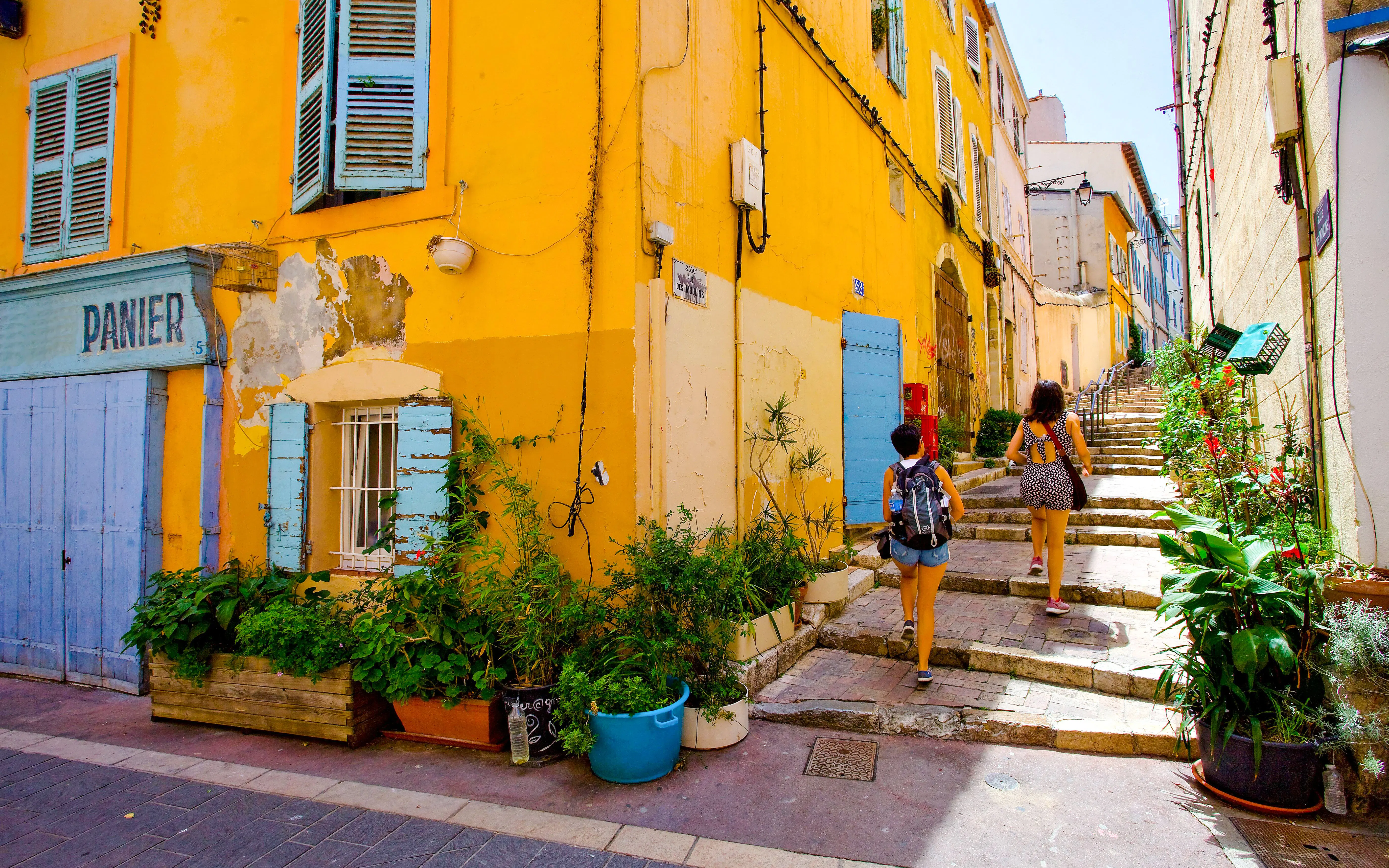 Colorful street in Le Panier, Marseille with people walking up stone steps.